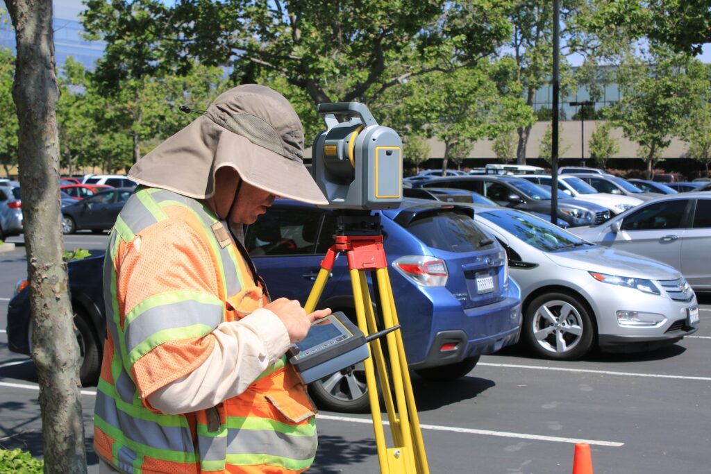 A surveyor using a measuring tool to take measurements of a property boundary.